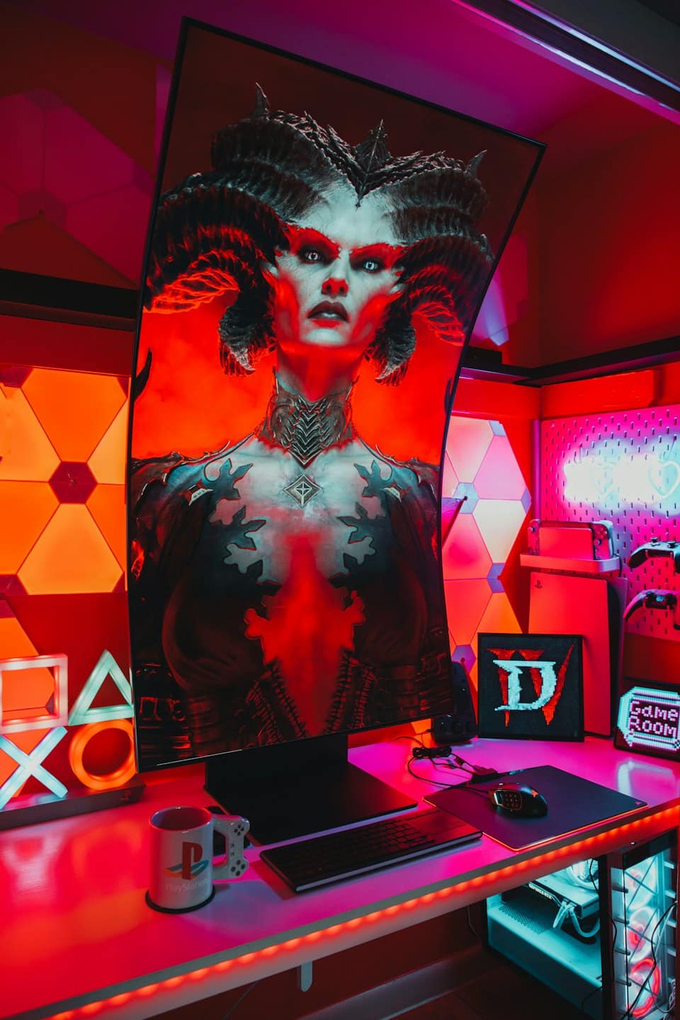 Scrivania da gaming con monitor curvo, tastiera e simboli PlayStation.