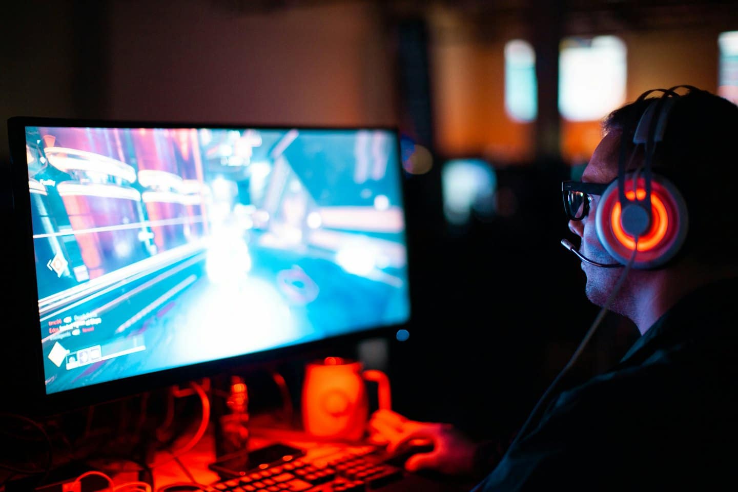 Un giocatore con le cuffie gioca ai videogiochi su uno schermo di computer luminoso.